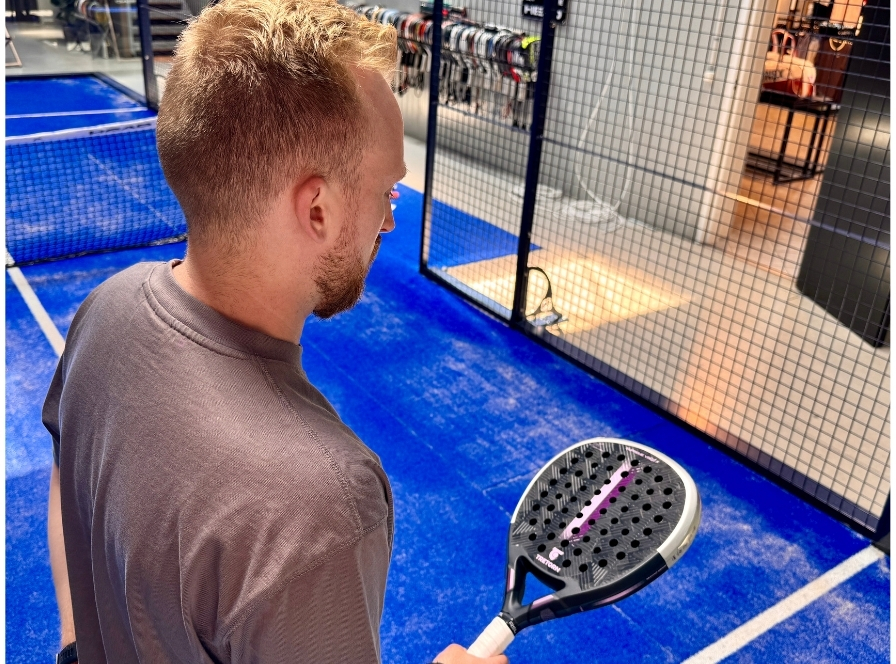 Man testar tretorn padelracket för avancerade spelare på inomhusbana hos Padelshoppen